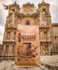 Bag of Oaxaca Reserve coffee in front of Oaxaca cathedral with monarchs flying